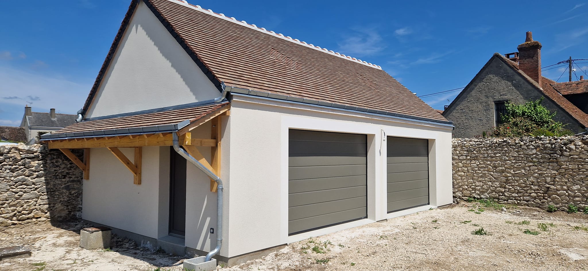 Construction d'un Bâtiment enduit avec deux portes de garages en alu et un porte d'entrée sous une pergolas