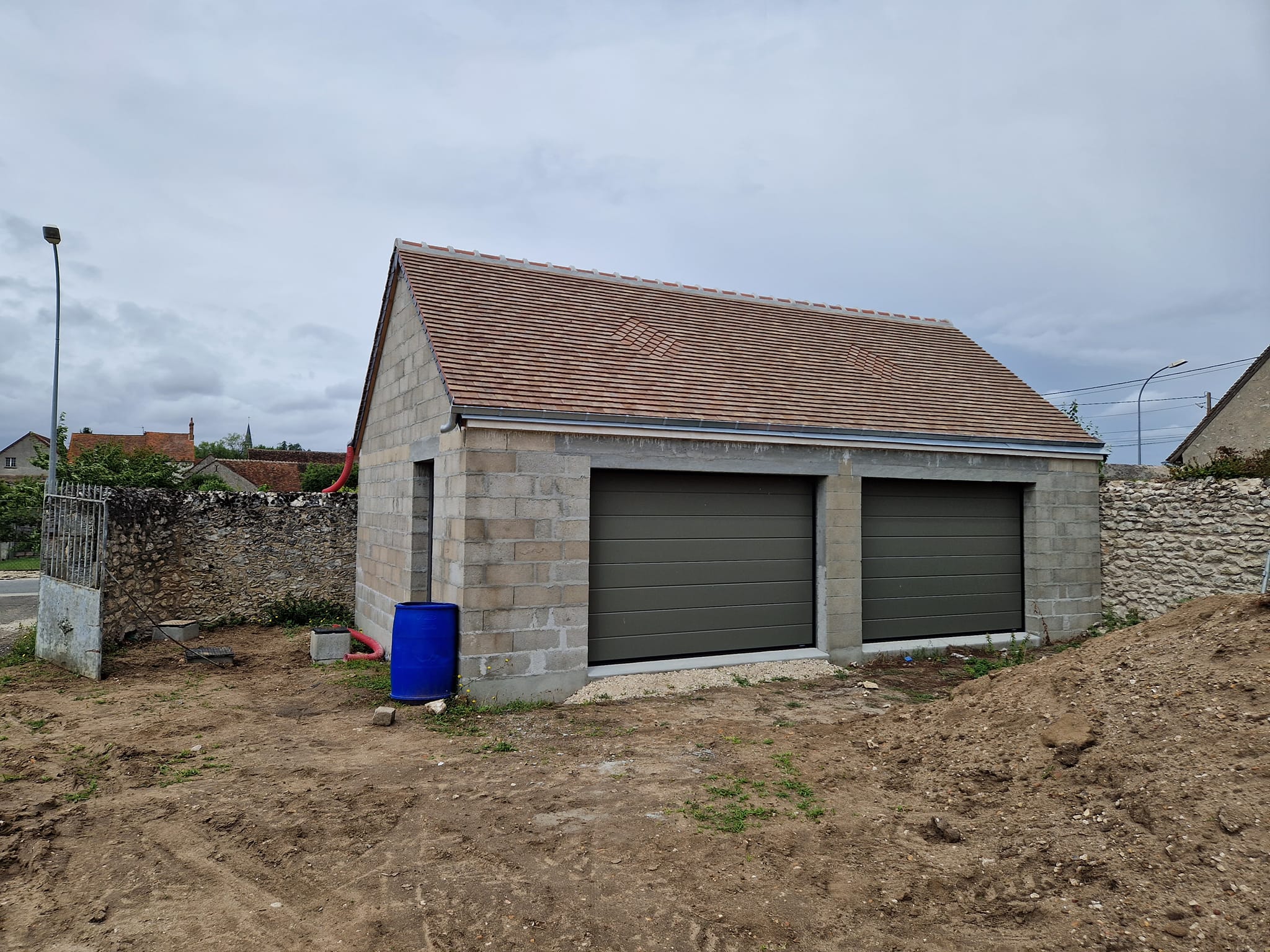 Bâtiment de parpaing en construction avec pose de deux porte de garage en alminium