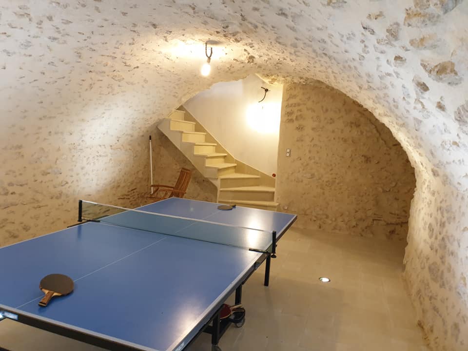 Cave avec voute en pierre. Une table de tennis de table est positionné au centre