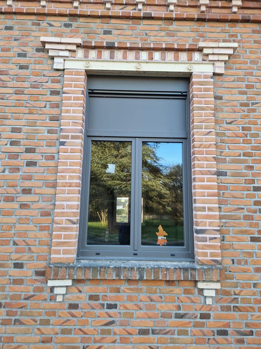 Pose de fenêtre en aluminium sur une maison en brique