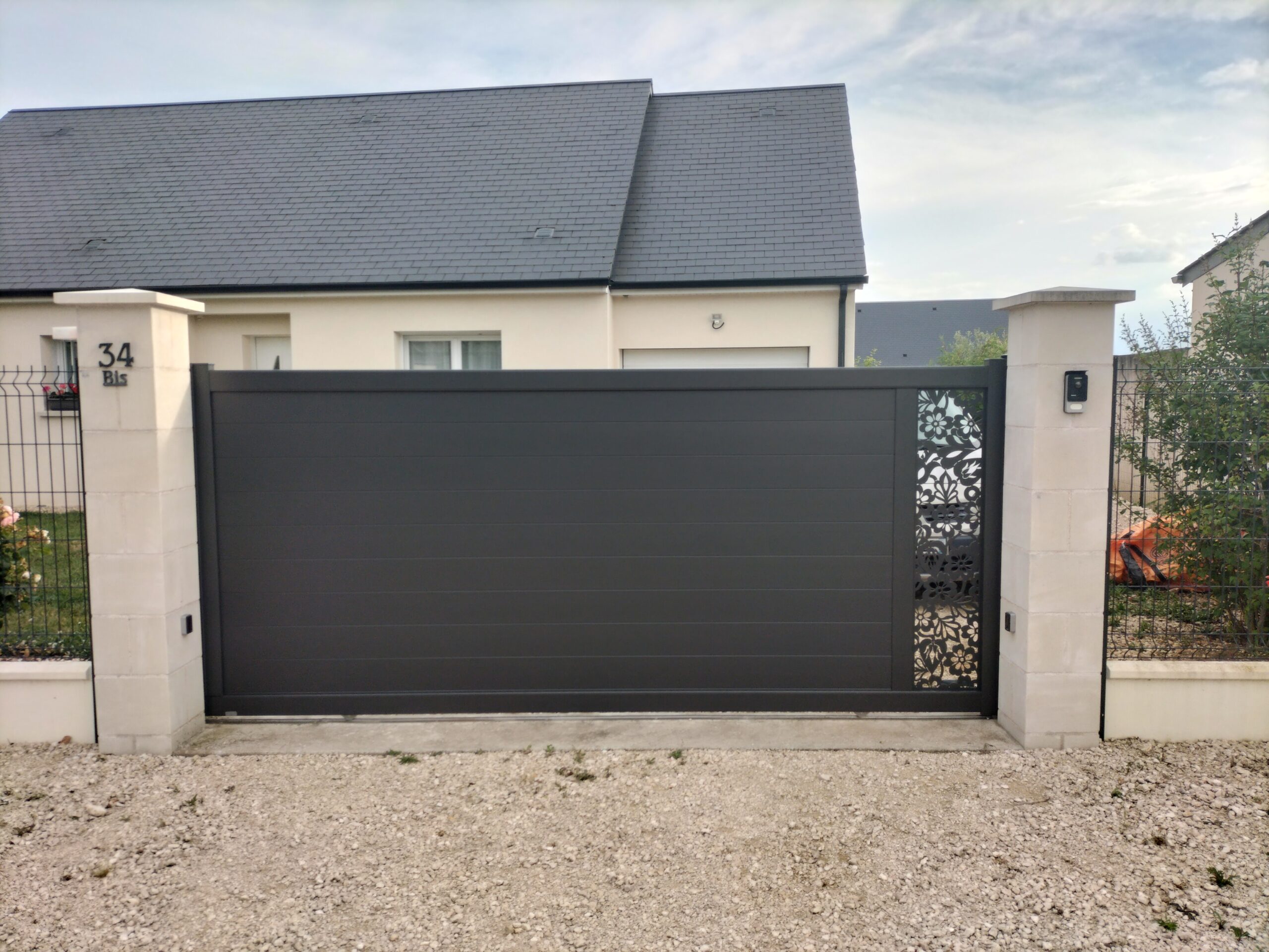 Portail coulissant en aluminium avec élément décoratif feuille et fleurs sur la partie droite