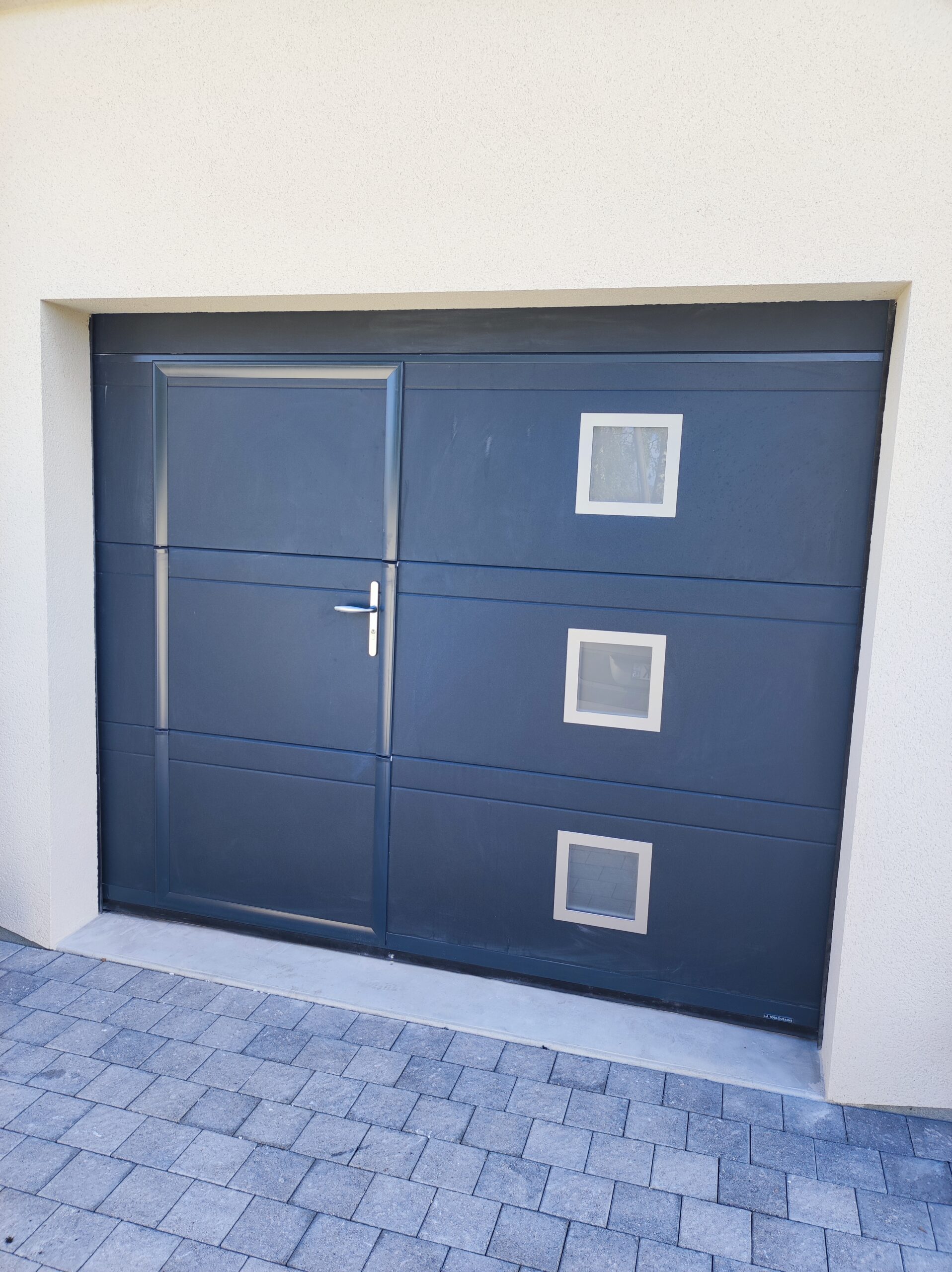Porte de garage en aluminium avec porte d'entrée intégrée.