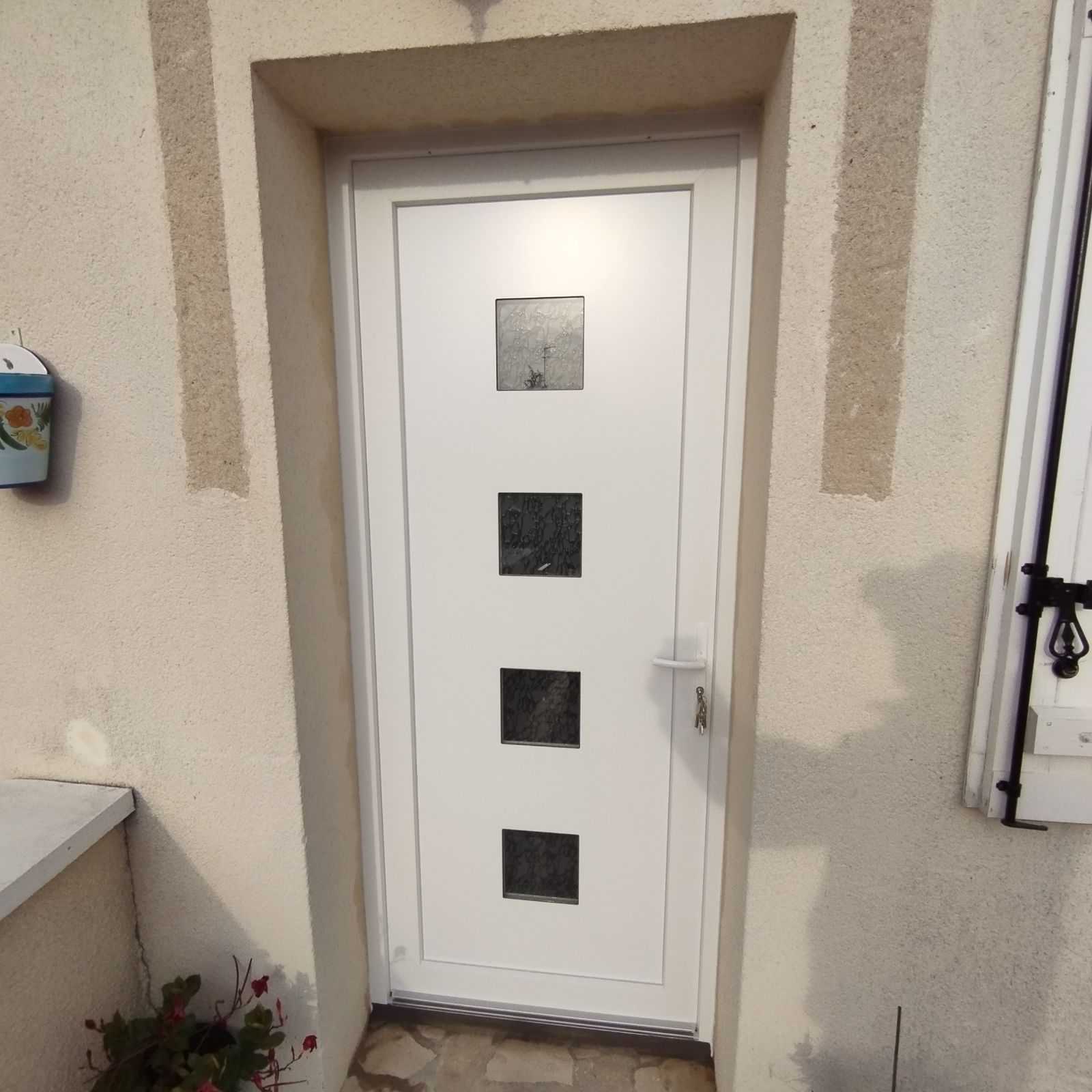 Porte d'entrée avec 4 vitrages carrés pour laisser passer la lumière vue de l'extérieur