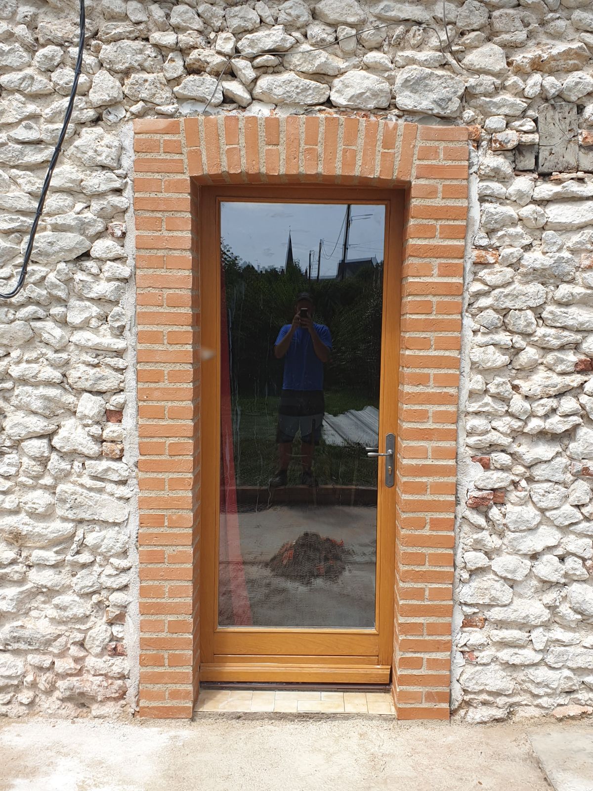 Porte vitrée entourée de brique sur une maison en pierre