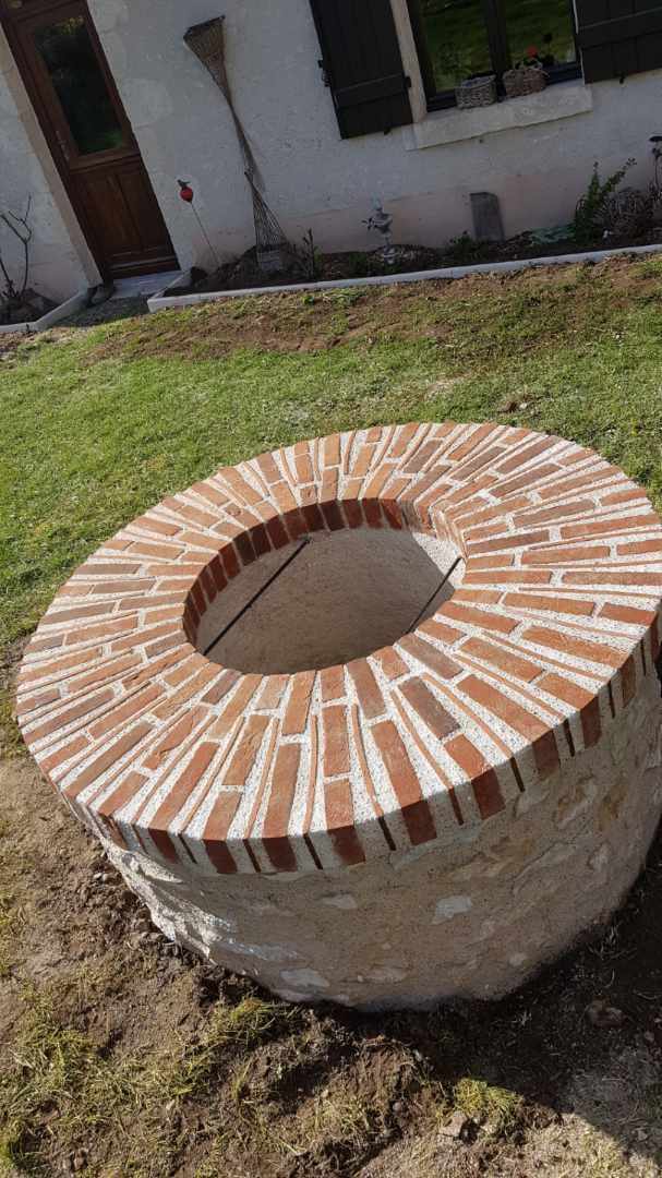 Travaux de maçonnerie sur un puit en pierre et en brique