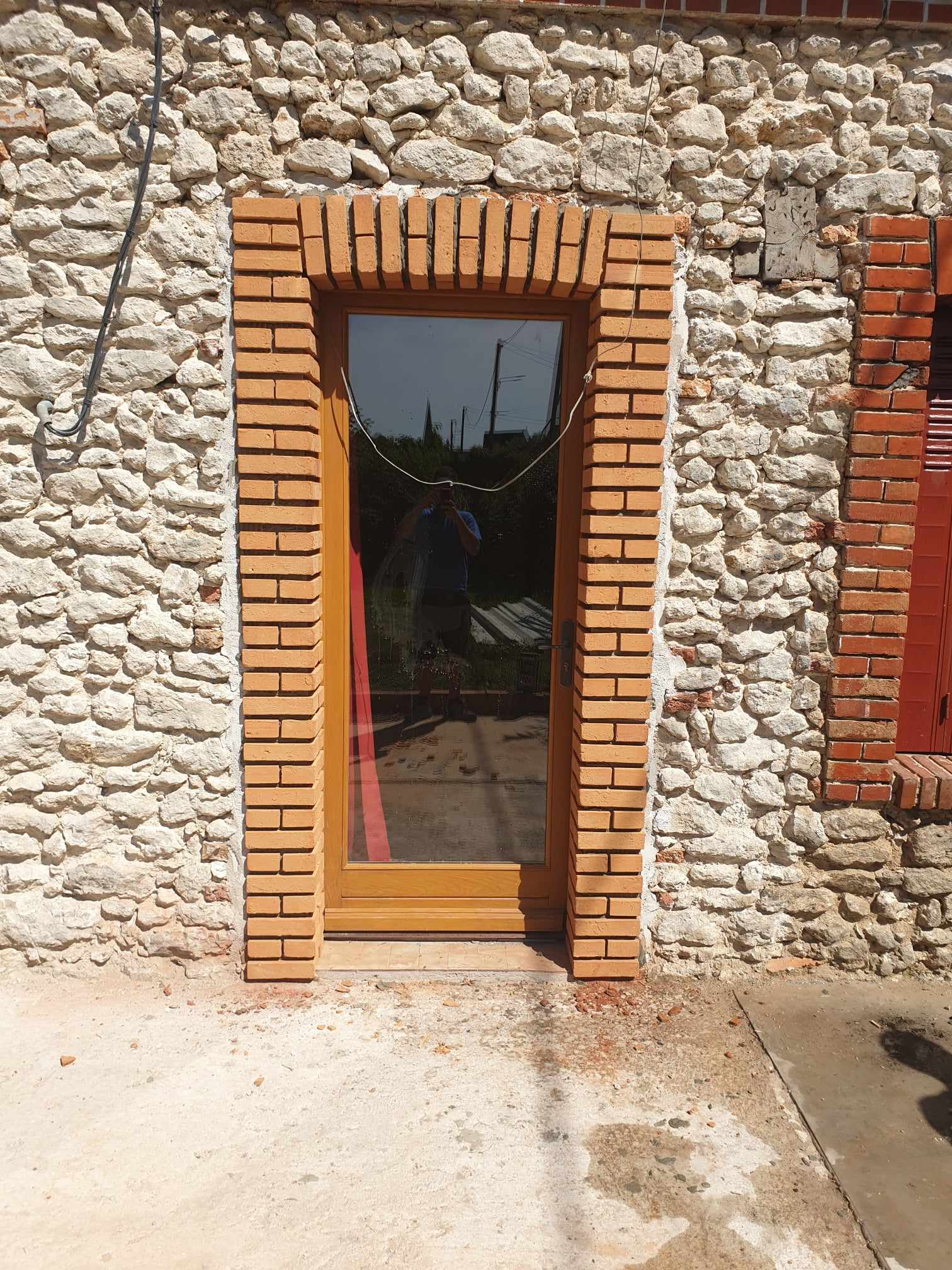Porte vitrée entourée de brique sur une maison en pierre
