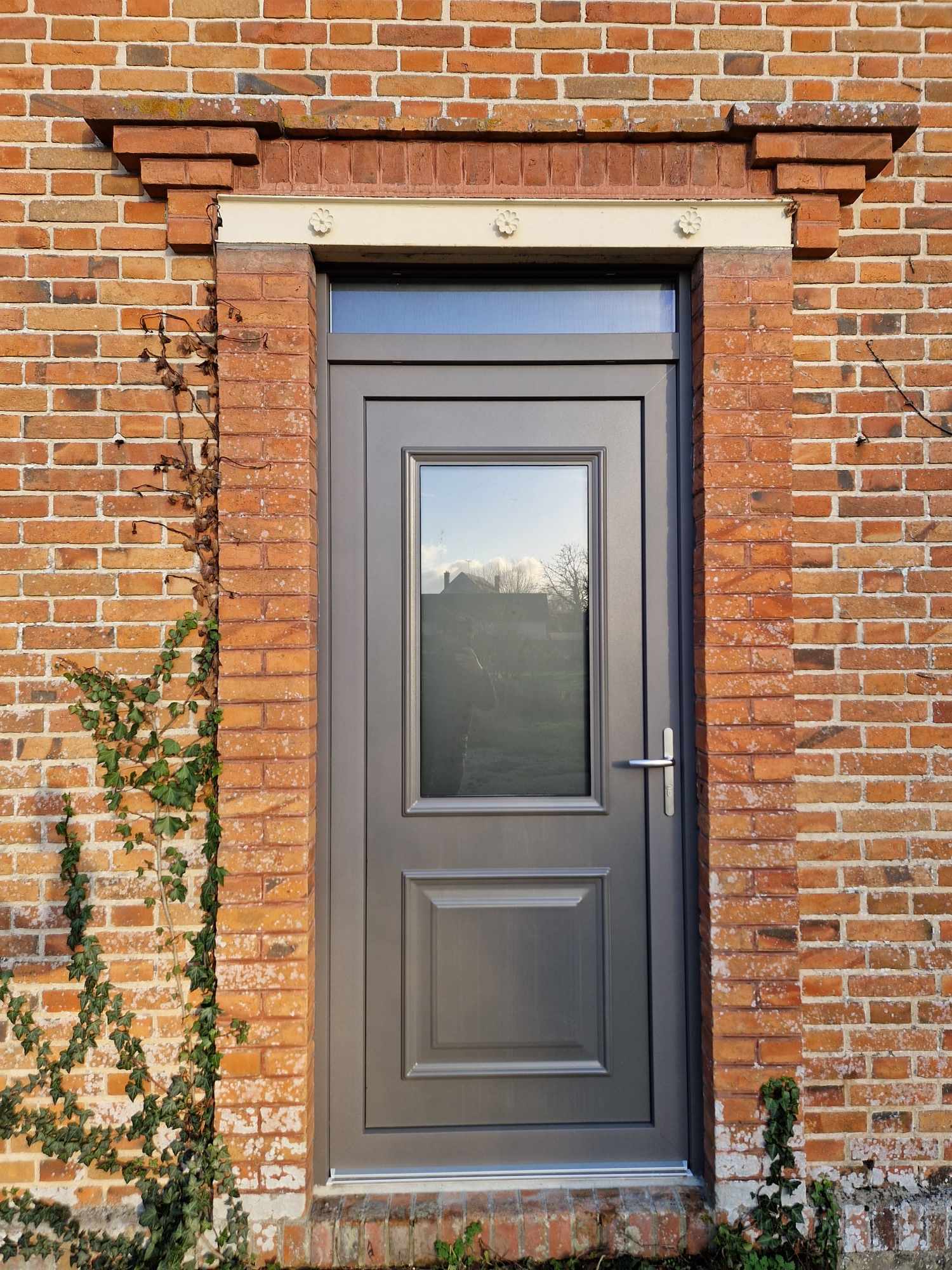 Porte d'entrée en aluminium avec vitrage dépoli sur une maison en brique